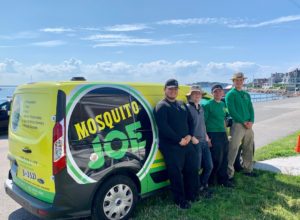 A group of Mosquito Joe technicians standing next to yellow service van.