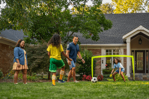 Family playing soccer outside in backyard. 