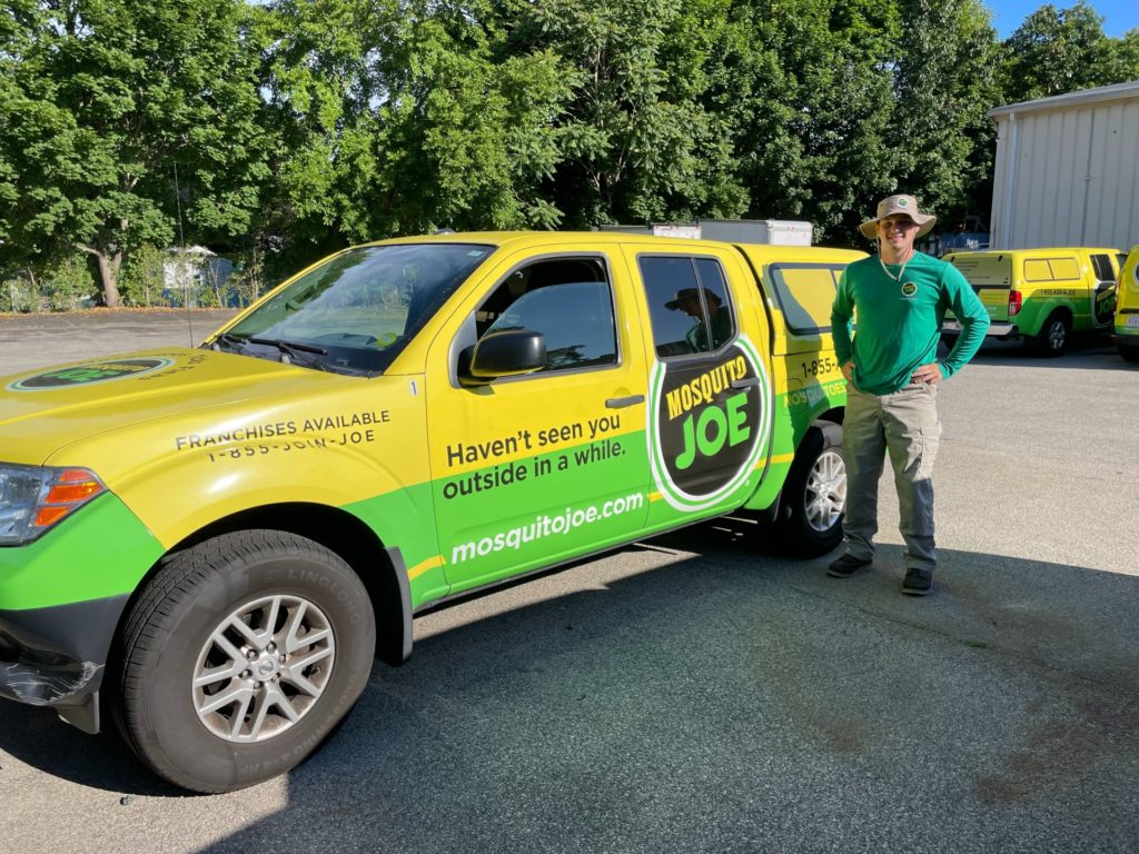 Field Technician, Hudson, standing in front of yellow and green Mosquito Joe truck, ready to help customers take back their yard from mosquitoes and ticks in northern Fairfield County.
