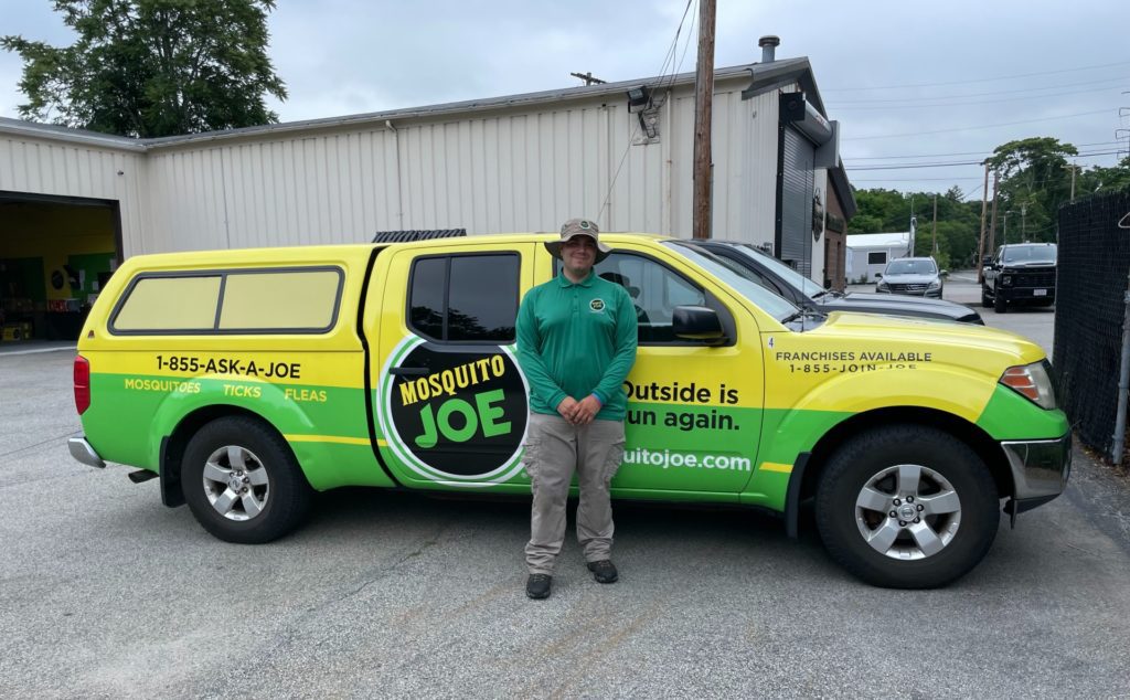 Zach, Lead Technician for Mosquito Joe of Northern Fairfield County standing in front of yellow and green Mosquito Joe truck.